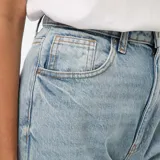 Pantalón de jean celeste de corte recto, tiro alto y con dobladillo ancho en el ruedo.