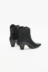 Bota corta de cuero negro con taco medio y punta fina. Presenta recortes grabados en el mismo material en el cuerpo de la bota.