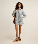 Short femenino de sarga con estampado de rayas verticales en azul y blanco. Cuenta con cintura alta elástica, bolsillos laterales y traseros, y bajo plegado. Confeccionado en 100% algodón.