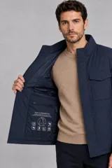 Campera de abrigo color azul marino, con cuello alto, cierre frontal oculto y dos bolsillos frontales con solapa.