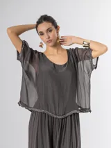 Vestido largo de seda italiana en color gris oscuro, con falda larga lisa, forro y cintura elastizada. Posee una sobrecapa con detalles de paillettes en los bordes de las mangas y la cintura.