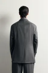 Blazer regular fit de Zara confeccionada en 100% lana, de color gris con diseño de rayas diplomáticas. Presenta cuello con solapas de pico, manga larga con botones en los puños, bolsillos con solapa en la cadera y bolsillo de vivo en el pecho. Cuenta con cierre frontal de botonadura cruzada.
