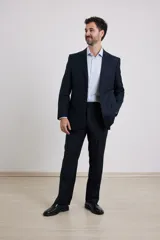 Traje de corte clásico compuesto por saco de dos botones y pantalón de vestir a juego. El saco presenta solapas tradicionales y bolsillos con solapa, mientras que el pantalón tiene un corte recto y formal.