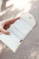 Billetera pequeña de cuero color dorado con cierre de solapa con broche a presión.