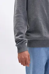 Buzo de tejido de punto en color gris, con cuello alto y cierre frontal parcial. Presenta puños y ruedo acanalados.