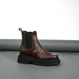 Bota tipo Chelsea de cuero vacuno, con suela de goma track de doble altura y elásticos laterales. Presenta una horma de punta cuadrada.