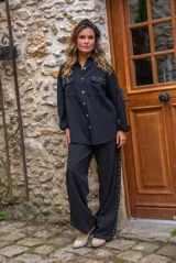 Camisa de denim negra con botones metálicos dorados y bolsillos con tachas doradas. De corte amplio.