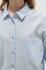 Camisa de algodón con estampado de rayas verticales finas, cuello camisero, cierre frontal con botones y bolsillos frontales tipo parche.