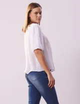Blusa blanca de gasa marca Zac & Rachel, con frunces en la parte delantera, mangas cortas con puño elastizado, abertura central en la espalda y botón.