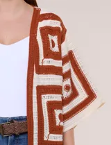 Cardigan largo confeccionado en tejido de punto calado estilo crochet, de color amarillo y blanco, con diseño geométrico de cuadrados, mangas amplias tipo kimono y corte abierto al frente.