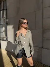 Blazer de corte entallado con diseño a rayas verticales, cuello solapa y cierre frontal de tres botones. Presenta mangas largas y un diseño asimétrico en el ruedo.