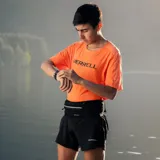 Riñonera deportiva minimalista marca Merrell, color negro, diseñada para trail running. Cuenta con cierre frontal, ajuste elástico y múltiples bolsillos para almacenamiento ligero.