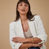 Esclava de alambre redondo en oro 9k, de diseño minimalista, con una medalla colgante que presenta un diseño grabado en forma de estrella con una circonia incrustada.