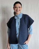 Chaleco tejido de punto color lila, sin mangas y con cuello abierto.