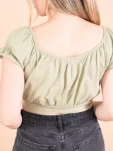 Top corto color mostaza con escote cuadrado, mangas cortas abullonadas con elástico y detalle cruzado en el frente.