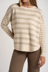 Sweater de punto con cuello redondo, manga larga y diseño de rayas horizontales alternando beige claro y beige melange. Presenta un calce ajustado y un ruedo con aberturas laterales redondeadas.