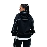 Campera deportiva unisex de color negro con cierre frontal completo y detalles de costuras en color blanco. Presenta capucha con cordones ajustables, bolsillos laterales y un diseño de líneas curvas que recorren el frente y las mangas.