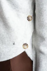 Sweater de punto gris melange con cuello redondo, manga larga y detalle de botones laterales en el costado.