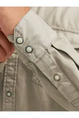 Camisa de denim color beige, con cuello clásico, cierre con botones y dos bolsillos frontales con solapa abotonada. Corte slim.