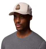 Gorra snapback Flexfit® color beige con visera curva y logo bordado de una montaña en tonos tierra y verde.