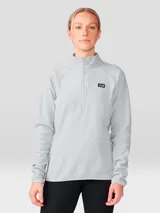 Buzo polar de mujer con cierre frontal de un cuarto, cuello alto y mangas raglán. Presenta un diseño minimalista en color gris claro con el logo de la marca bordado en el pecho.