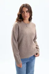 Buzo de tejido de punto en color beige, con cuello redondo a la base, mangas largas y puños y ruedo acanalados.