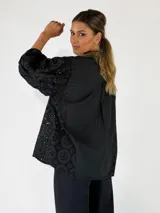 Camisa blanca con cuello camisero, cierre frontal de botones y mangas tres cuartos abullonadas con bordados suizos y detalles perforados en los laterales y mangas.
