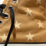 Championes Converse Chuck 70 de caña alta, color marrón con estampado de estrellas en tono crema. Presentan puntera de goma blanca, cordones negros y el icónico parche circular de la marca en el lateral.