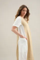 Vestido largo de lino de silueta relajada, con escote redondo, mangas cortas y bolsillos laterales. Cuenta con un diseño bicolor que combina un panel central en color tostado y los laterales y mangas en color blanco.