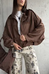Campera tipo bomber de gamuza color chocolate, con diseño oversize, mangas amplias y apliques decorativos en los hombros. Cuenta con cierre frontal y forro interior.