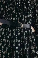 Cinturón negro con textura de cocodrilo y hebilla metálica dorada de forma ovalada.