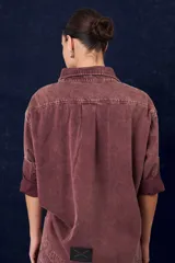 Camisa de gabardina con cuello clásico, cierre frontal de botones y mangas largas con puños vueltos. Presenta un diseño de corte recto y acabado desgastado.