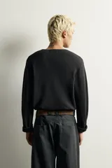 Camiseta relaxed fit de punto negro tejido en hilatura de algodón, con cuello redondo, cierre frontal de botonadura y manga larga con acabado en rib.