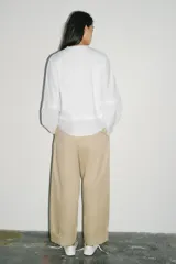 Camiseta oversize de cuello redondo y manga larga con puños abotonados. Confeccionada en algodón, presenta un diseño con combinación de tejidos a tono y bajo asimétrico.