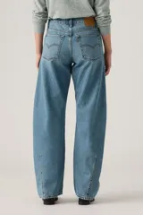 Pantalón de jean de corte baggy con diseño barrel, tiro medio y lavado azul claro con efecto desgastado. Presenta costuras laterales curvadas que definen su silueta amplia y relajada.