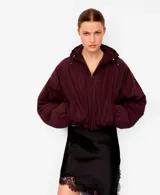 Chaqueta puffer corta color bordó, con capucha ajustable, cierre frontal y bolsillos laterales, de mangas abullonadas y diseño holgado.