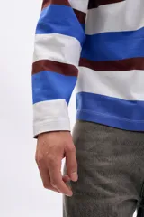 Remera de manga larga tipo polo con cuello camisero y cierre frontal de botones. Presenta un diseño de rayas horizontales anchas en tonos azul, blanco y marrón.