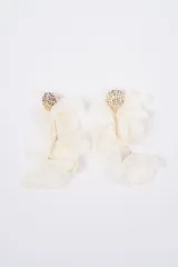 Aros colgantes con base circular de metal dorado texturizado y pétalos de tela en color crema dispuestos en capas.