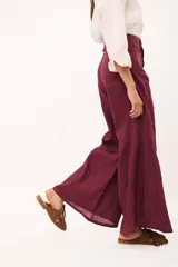 Pantalón de tiro alto, pierna ancha y largo, color beige claro con finas rayas verticales en tono oscuro. Presenta un diseño de cinco bolsillos estilo jean.