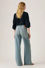 Jeans de corte recto y tiro alto, con diseño de pierna ancha y acabado lavado en tono celeste claro. Presentan cierre frontal con botón y cremallera, además de bolsillos laterales y traseros.