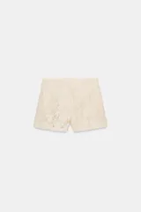 Shorts de tiro alto confeccionados en encaje con diseño floral. Presentan bolsillos delanteros y cierre frontal con cremallera y gancho metálico.