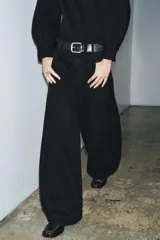 Pantalón de jean negro de tiro bajo, corte amplio tipo balloon, con cinco bolsillos y cierre frontal con cremallera y botón.