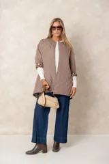Campera acolchada de corte amplio y largo midi, color beige con diseño capitoneado. Presenta mangas tres cuartos con puños vueltos que revelan un interior estampado con motivo animal print. Diseño sin cuello y cierre frontal oculto.