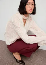 Pantalón de vestir color bordó, de tiro alto y diseño recto, con bolsillos laterales y cierre oculto con botón, gancho y cremallera.