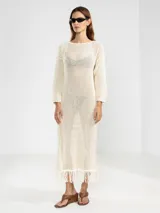 Vestido largo color crudo, tejido en punto abierto de algodón con lúrex y flecos en el ruedo.