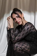 Vestido largo de encaje negro con transparencias, mangas largas y cuello redondo, acompañado de un top y un short interior a juego.