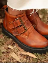 Botas cortas negras de cuero sintético con plataforma y suela track. Presentan dos correas con hebillas doradas y tirador trasero.