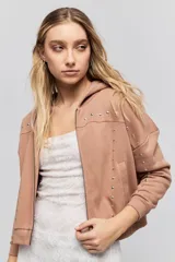 Campera tostada de calce relajado con capucha, cierre frontal, bolsillos laterales y detalles de tachas metálicas.