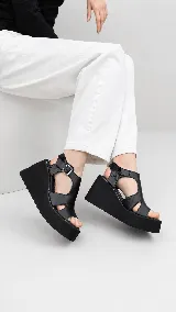 Sandalias de plataforma corrida color beige, con capellada de cuero y tira ajustable con hebilla en el tobillo.