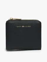 Billetera compacta Tommy Hilfiger de diseño cuadrado, confeccionada en material sintético con textura granulada. Cuenta con cierre perimetral metálico dorado y logo de la marca aplicado en letras metálicas doradas en el frente.
